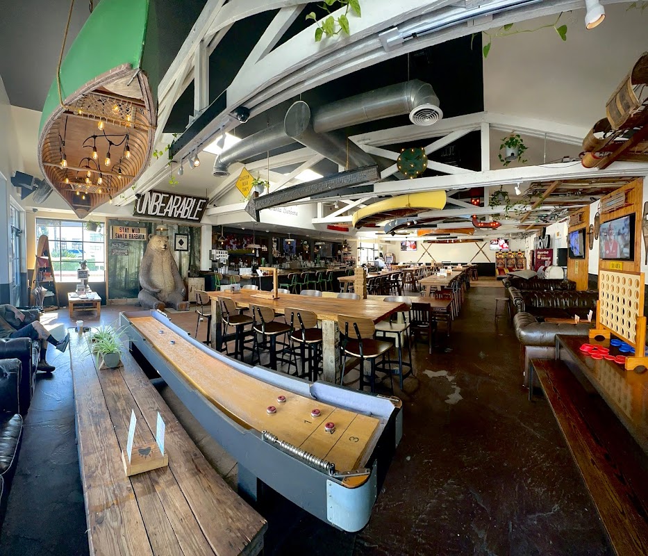 Wide-angle interior of Unbearable Skee Lodge showing the shuffleboard table, bar, dining area, and full venue space — perfect for large private events